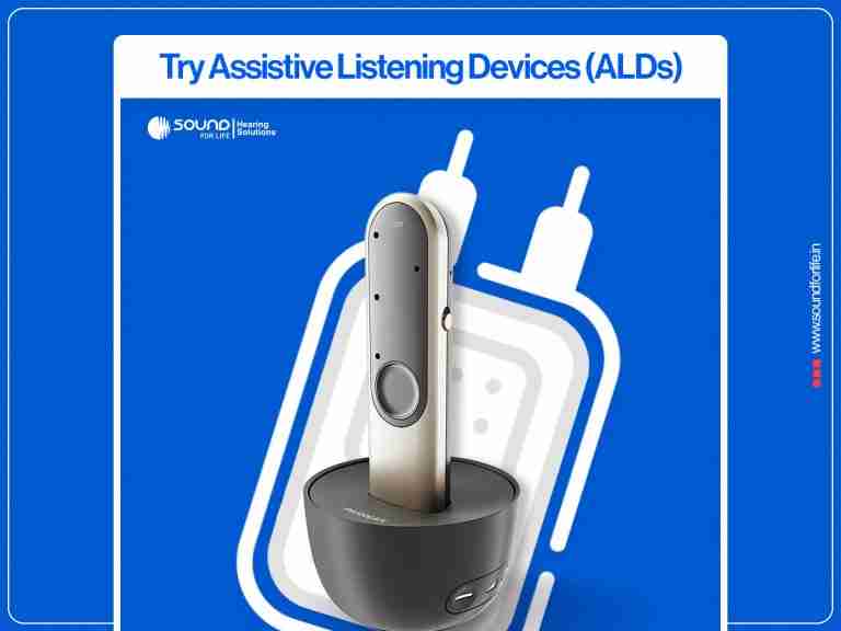 An assistive listening microphone device resting in its circular charging dock against a blue promotional background with the heading "Try Assistive Listening Devices (ALDs)".